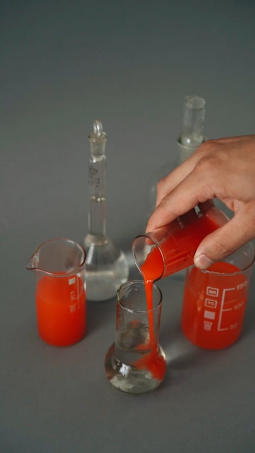 A Person Pouring a Chemical into a Flask