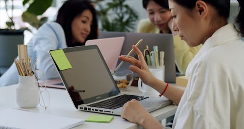 A Woman Writing on a Sticky Note in an Office