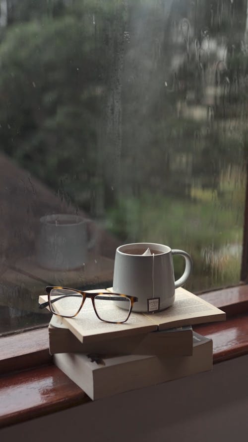 A Cup of Tea on Top of a Stack of Books by a Windowsill