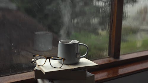 A Cup of Tea on Top of a Pile of Books by a Windowsill