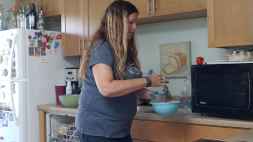 A Woman Placing Plastic Containers inside a Microwave