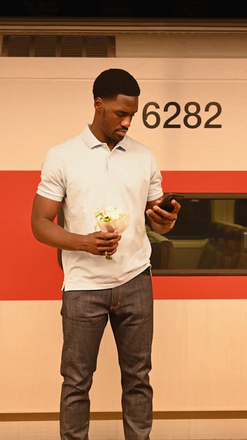 Man Checking his Phone and Holding Flowers
