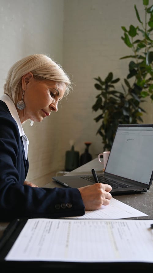 An Elderly Woman Writing on a Piece of Paper