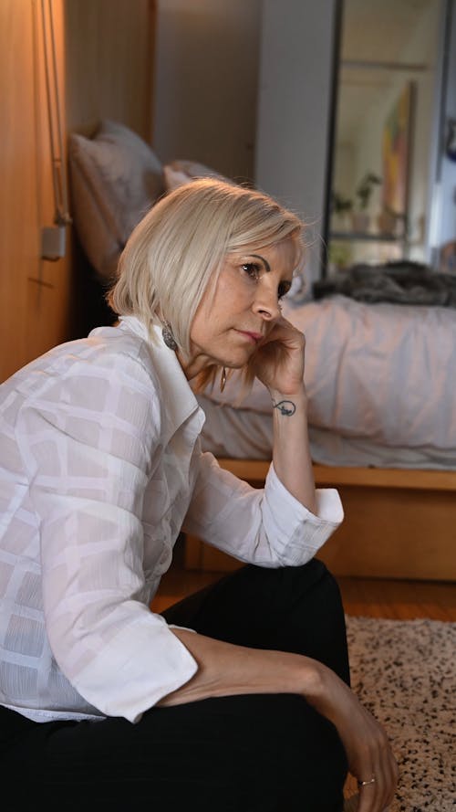 An Elderly Woman in Deep Thought while Sitting in the Bedroom