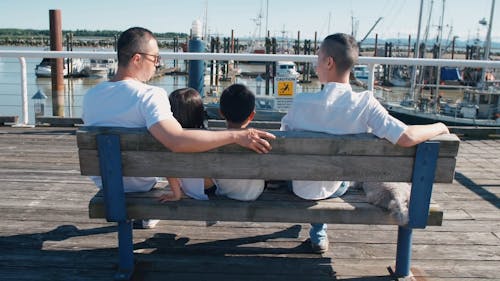 Back View of Family Sitting Close to Each Other on a Wooden Bench