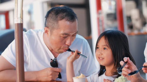 Cute Girl Feeding Her Dad with Ice Cream