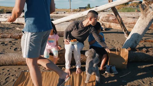 Family Sitting on a Log while Eating Snacks