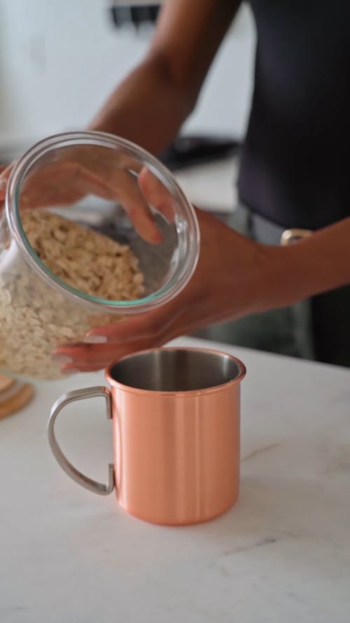 Person Pouring Oats on a Cup 