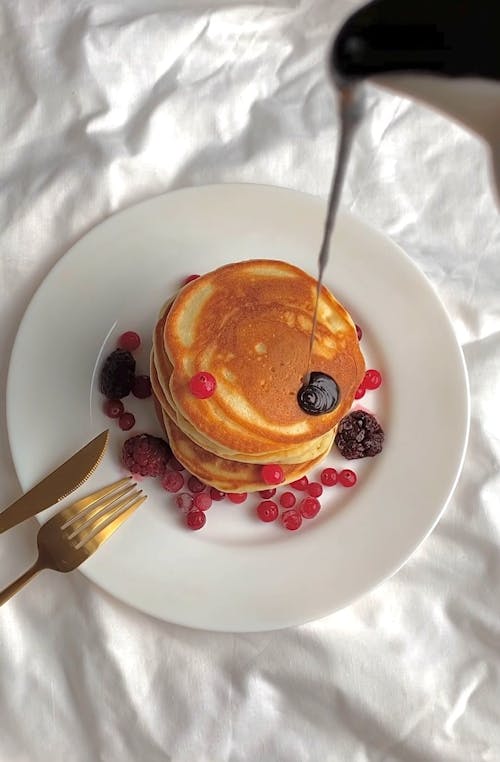 Person Pouring Chocolate on Pancake