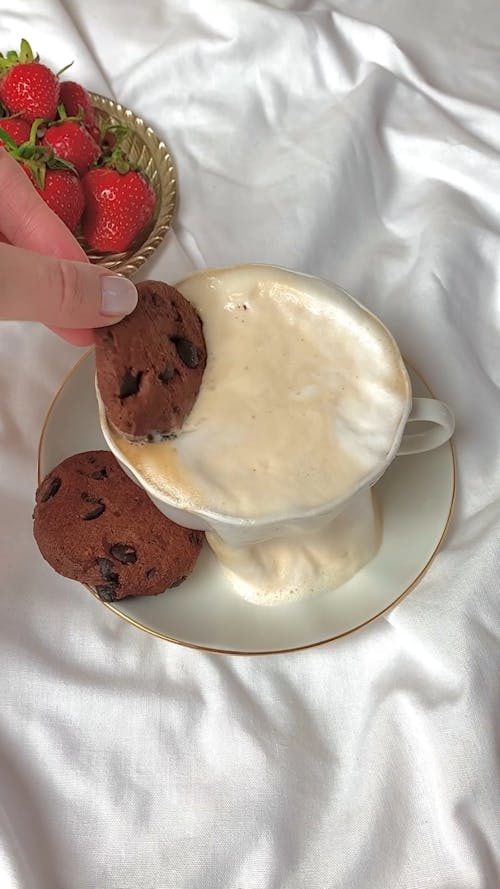 Person Putting Chocolate Chip Cookie on a Coffee