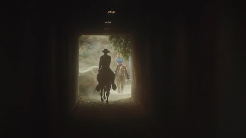 People Riding Horses Entering a Tunnel