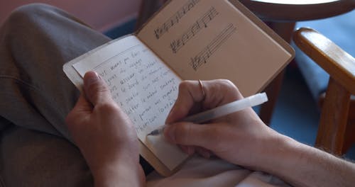 A Person Writing in French using Pen and Notebook