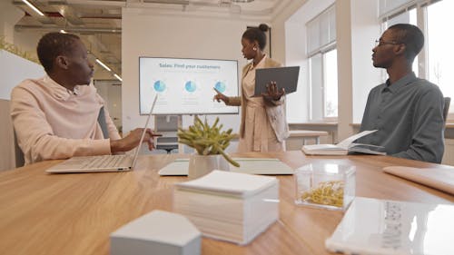 Woman Holding a Laptop While Presenting in a Meeting