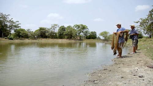 Fisherman Throwing A Net In The Pond To Catch Fish