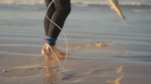 A Man Walking on the Beach while Carrying His Surfboard