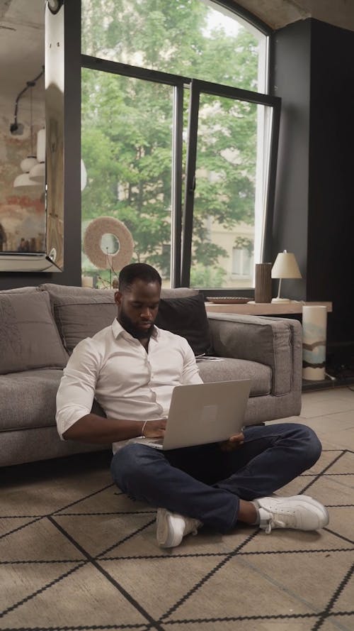 Man Sitting on the Floor while Using His Laptop