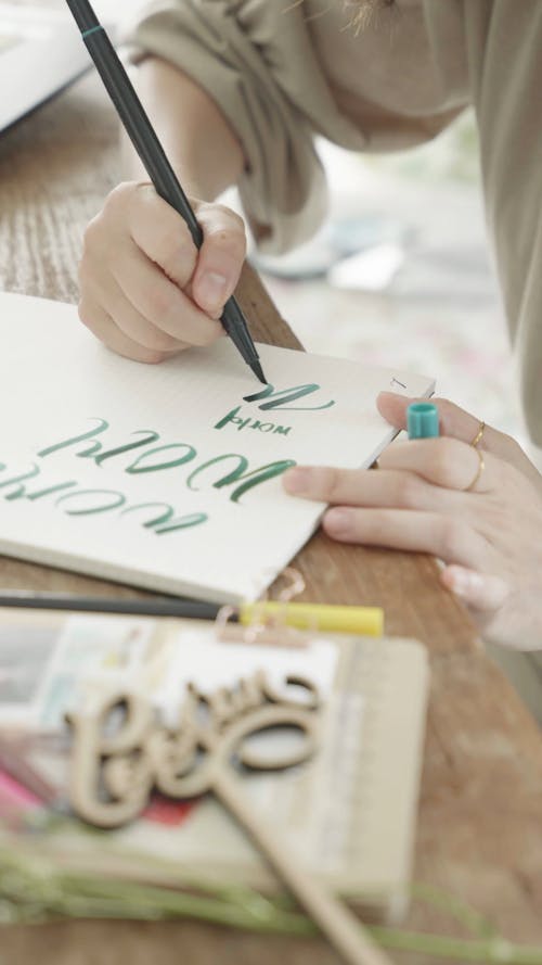 A Person Writing on a Paper using a Brush Pen