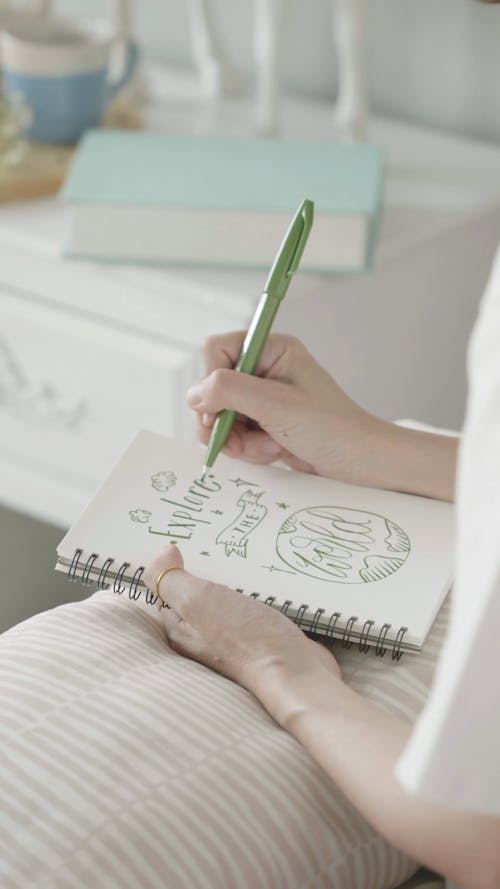 Person Writing on a Notebook with a Pen