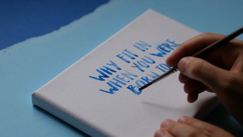 A Person Writing on an Art Board Using Paintbrush