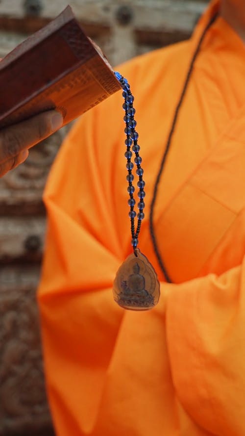 Person Holding a Book With Prayer Beads