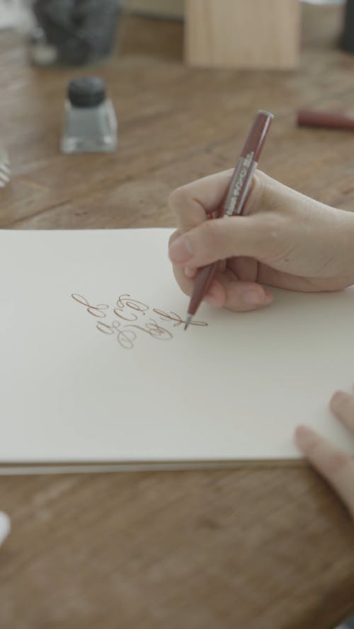 A Person Doing A Calligraphy On A Paper 
