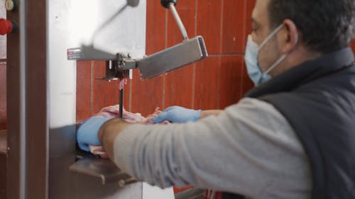 Close up of a Man Cutting Meat on a Band Saw