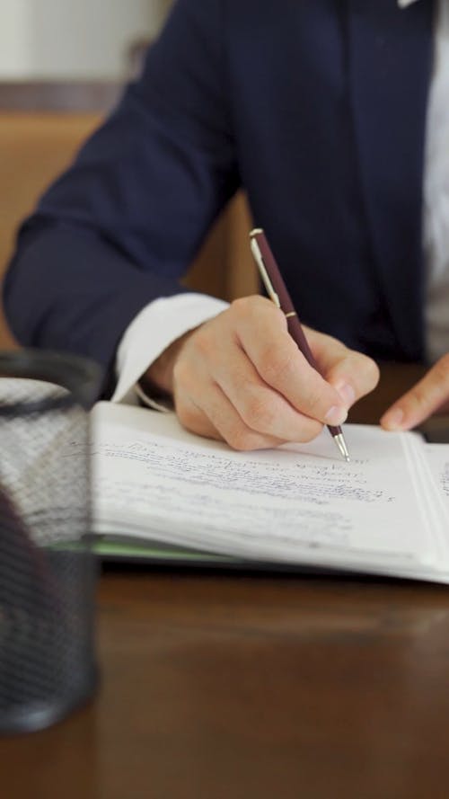 Person Writing on Notebook