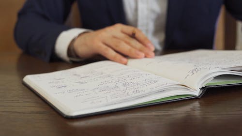 Person Writing on Notebook