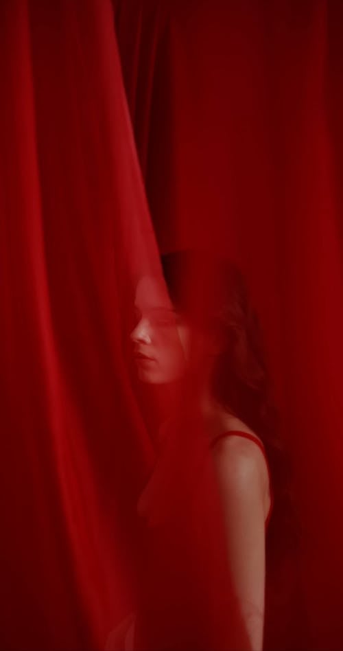 A Woman Posing in a Red Outfit behind Curtains