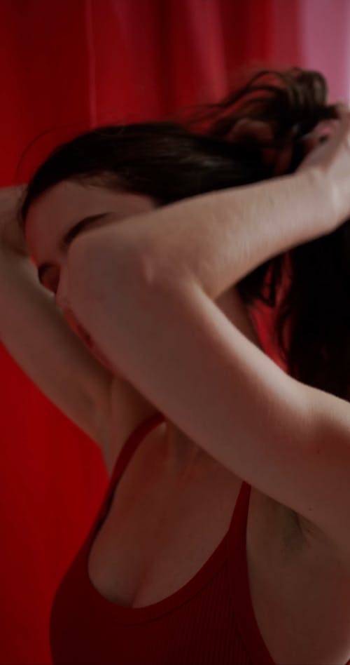 A Woman in Red Touching Her Hair