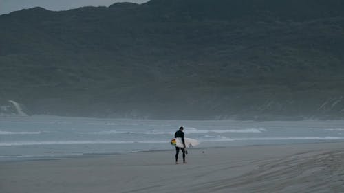 A Surfer Walking along a Beach