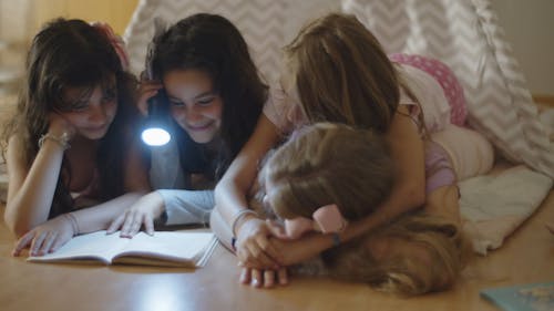Girls Reading a Book with a Flashlight