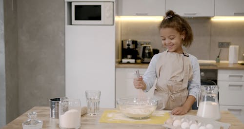 A Girl Mixing Flour on a Glass Bowl
