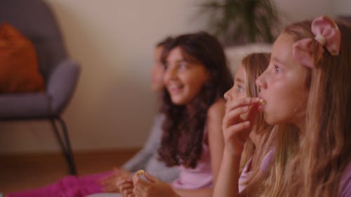 Young Girls Enjoying Watching while Eating Popcorn