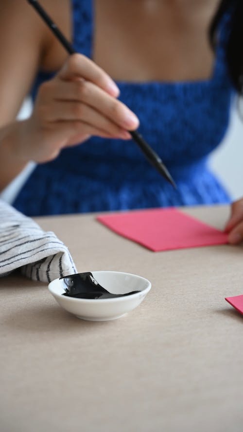 A Person Writing on Cards Using Ink and a Brush