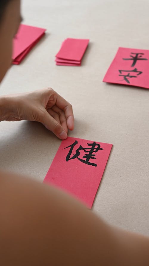 A Person Drawing Chinese Characters on Cards