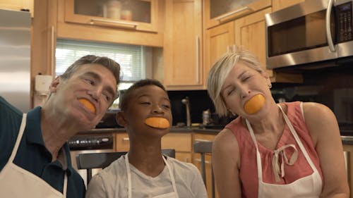 A Family Smiling with Orange Slices in their Mouths