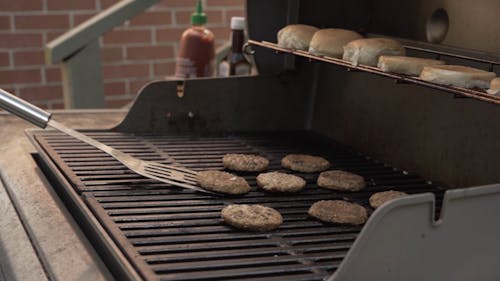 A Person Flipping a Burger Patty on a Grill