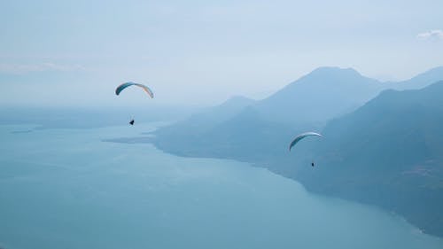 Paragliders Flying Over The Sea With Blue Water On A Foggy Day