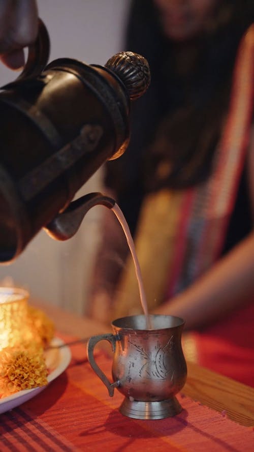 A Person Pouring Hot Tea on the Cup