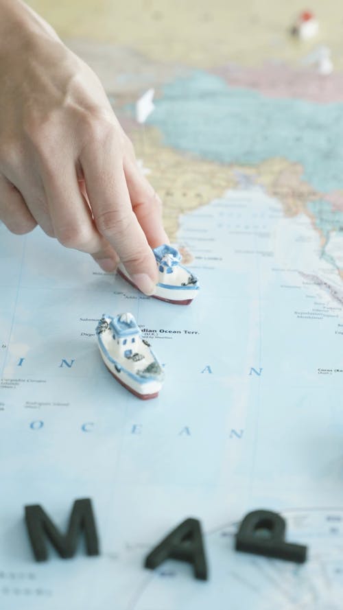 A Person Putting Toy Boats on a Map
