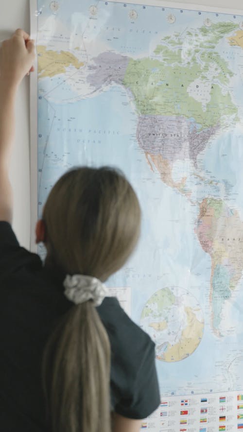 A Person Putting a World Map on a Wall