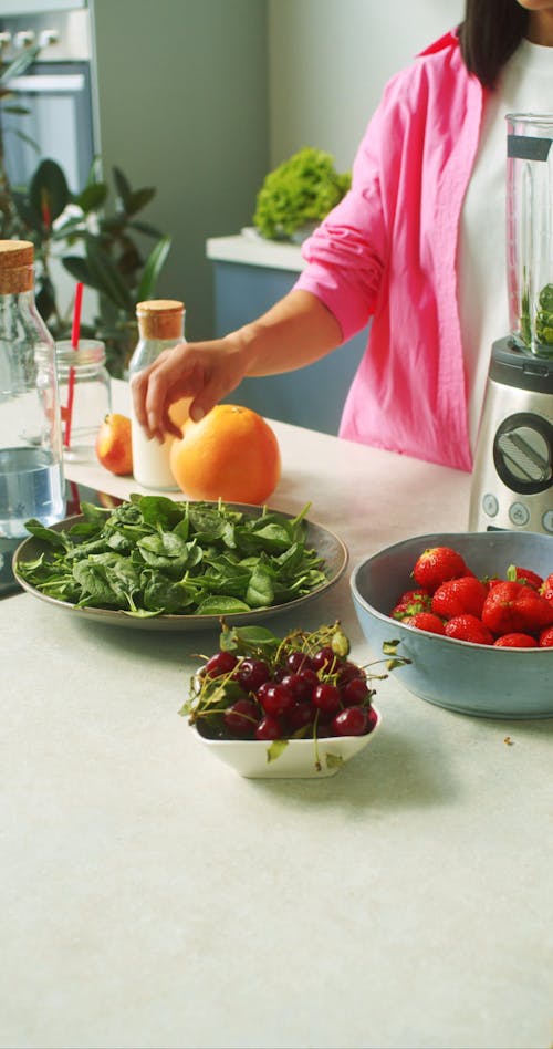 A Person Putting Ingredients on a Blender