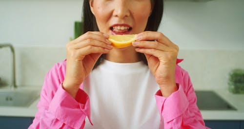 A Woman Tasting a Lemon