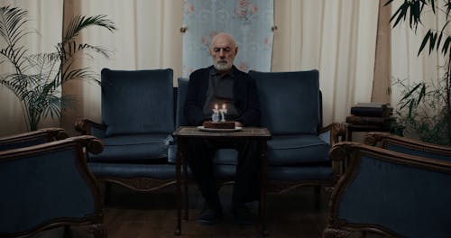 An Elderly Man Blowing His Birthday Candles