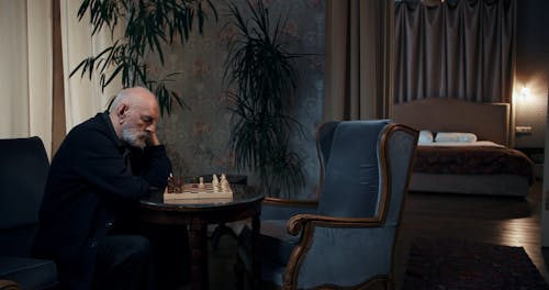 An Elderly Man Playing Chess Alone