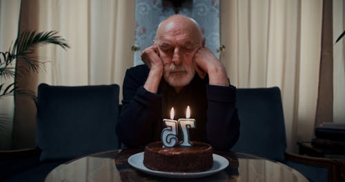 An Elderly Man Blowing His Birthday Candles