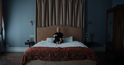 An Elderly Woman Sitting on a Bed