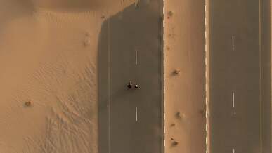 drone footage of two backpackers walking on a desert road