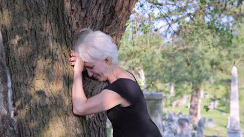 A Grieving Woman Crying while Leaning on a Tree Trunk